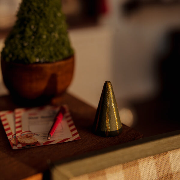 Abetos de madera en miniatura pintados en verde con pequeñas líneas doradas.