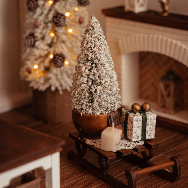 Trineo con abeto nevado, regalo, vela y chocolate